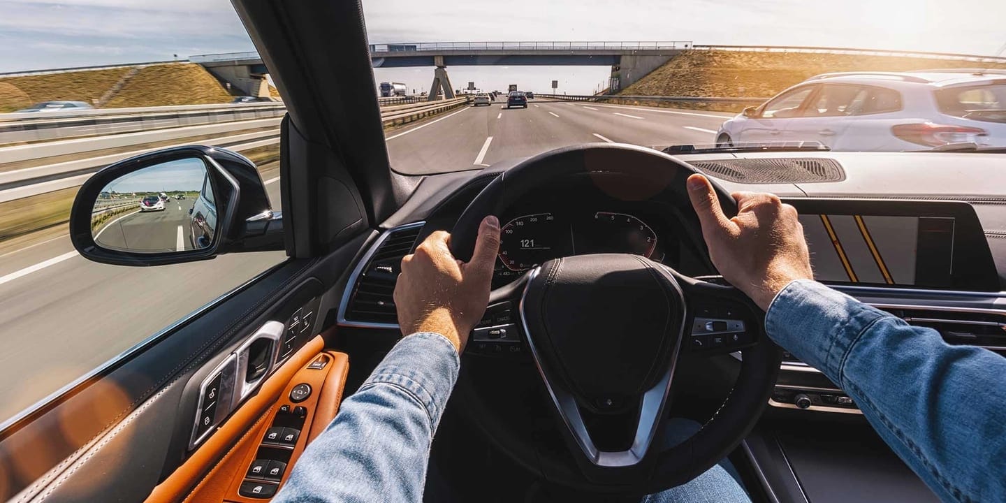 Hands holding the steering wheel of a driving car
