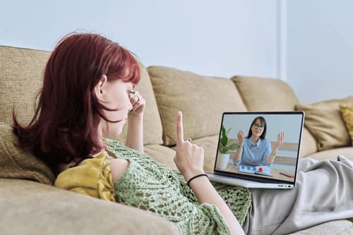 Young woman having an online therapy session from home via video call on her laptop.